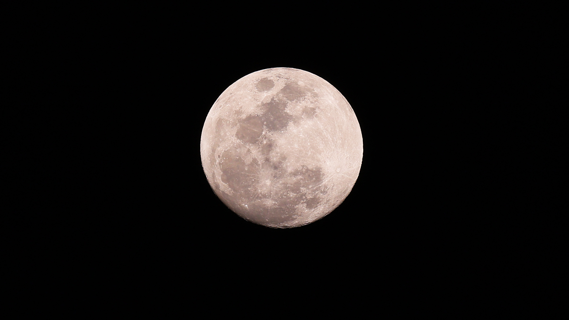 A full silver moon is depicted shining in a black night sky. The moon's dark oceans and small glowing craters can be seen marking its surface.