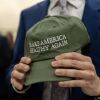 A close-up of hands holding a green baseball cap "Make America great again." 