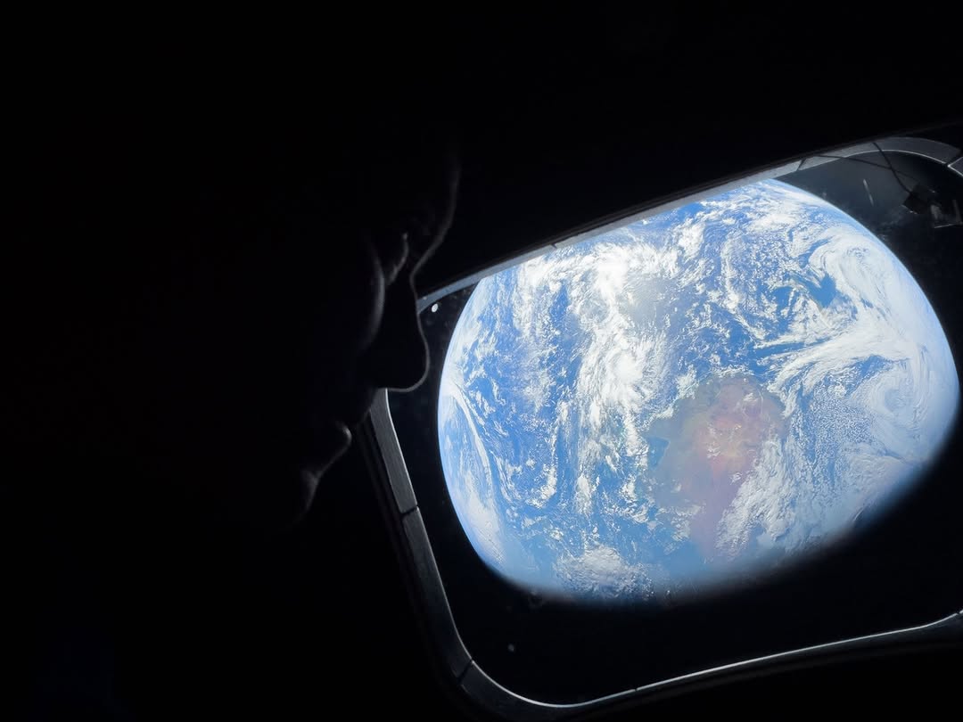 A man looks at the Earth from a window in his spaceship.