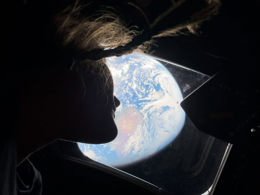 A photo of Artemis 2 astronaut Chistina Koch looking out the window at Earth/
