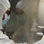 A scientist in a protective suit handling samples in a laboratory for ancient DNA analysis