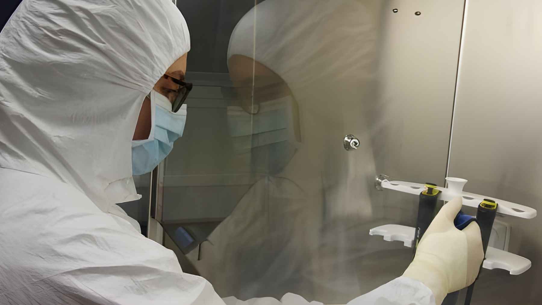 A scientist in a protective suit handling samples in a laboratory for ancient DNA analysis