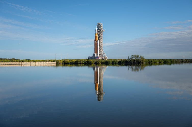 A rocket on a launch pad overlooking the water.